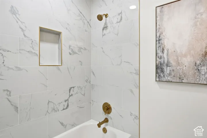 Bathtub with a gold-finish showerhead, gold-finish faucet, and a tiled surround