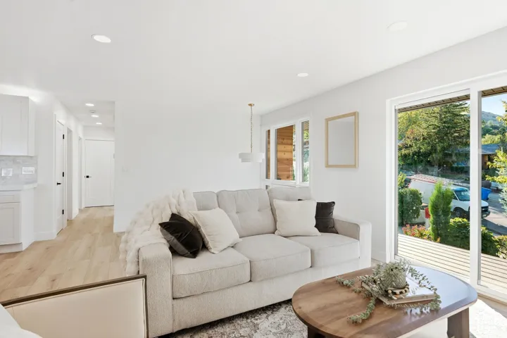 Light wood-finish flooring, recessed ceiling lighting, white walls, and a large sliding glass door