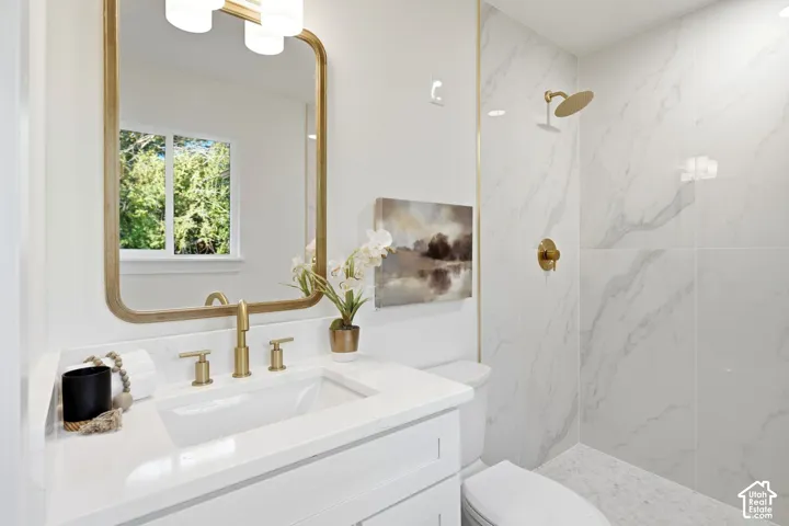White vanity with a rectangular undermount sink, gold-finish faucet, and white quartz-finish countertop