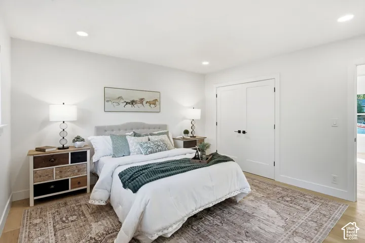 Recessed lighting, wood-finish flooring, white walls, and a light-colored headboard
