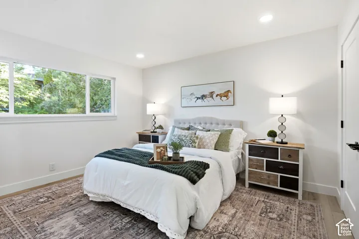 Recessed lighting, wood-finish flooring, white walls, and a large window
