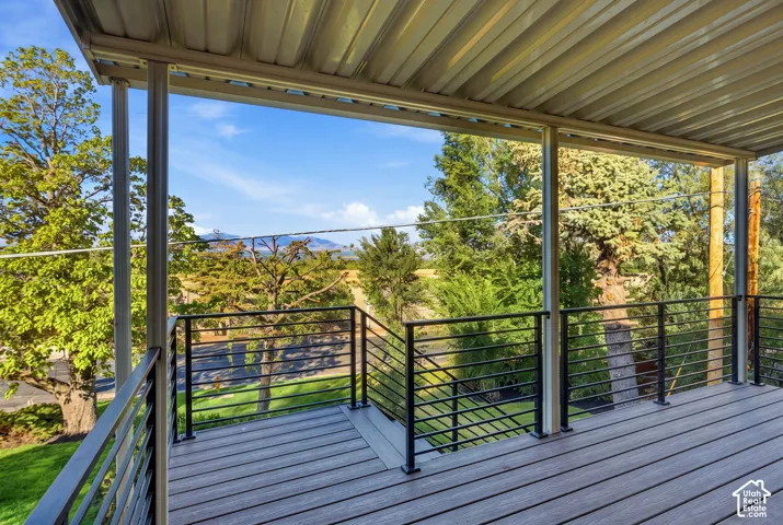Covered outdoor deck with composite decking, black metal railings, and a corrugated metal ceiling