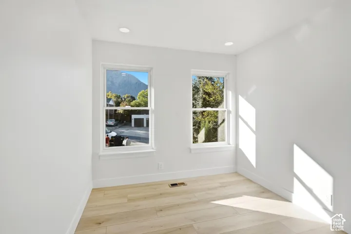 Bright room featuring two large windows, recessed ceiling lighting, and light wood-finish flooring