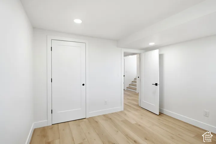 Recessed ceiling lighting, light wood-finish flooring, white flat-panel doors, and white walls