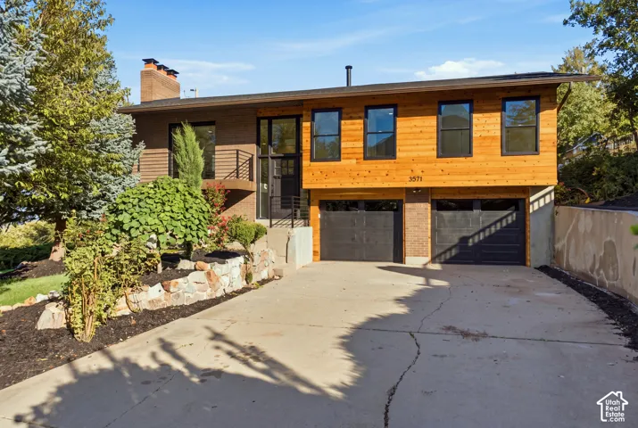 Multi-level exterior featuring wood-paneled siding, a brick facade, and black-framed windows