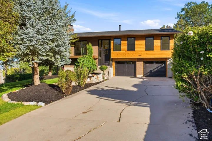 Split-level residence featuring wood paneling, dark-framed windows, and a two-car garage