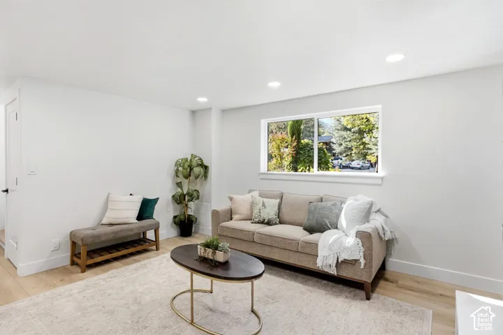 Recessed ceiling lighting, light wood-finish flooring, white trim, white walls, and a prominent window