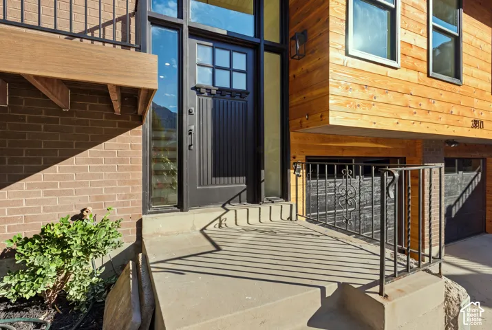 Brick and wood-paneled exterior with a black paneled entry door and adjacent full-length window