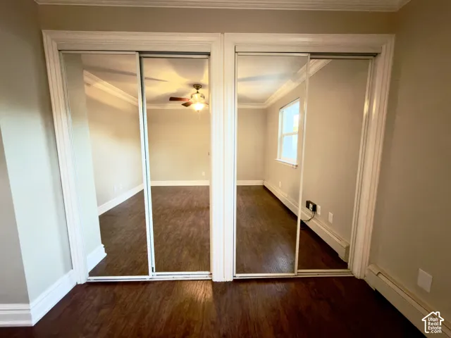 Mirrored double sliding closet doors with white trim, wood-finish flooring, and crown molding