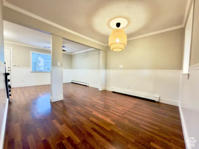 Dining & family room with laminate flooring, decorative wainscoting, crown molding, and a pendant light fixture