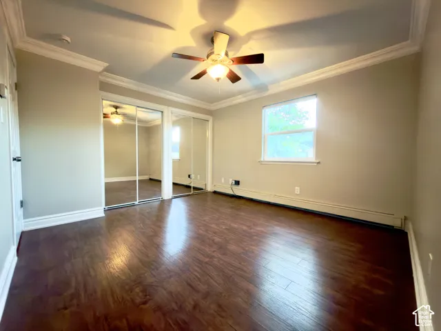 Laminate flooring, double mirrored sliding closet doors, crown molding, a ceiling fan with integrated lighting, and a window providing natural light