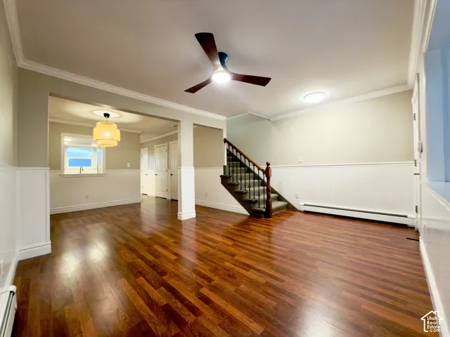 Laminate flooring throughout, wainscoting, crown molding, modern ceiling fan, and built-in staircase