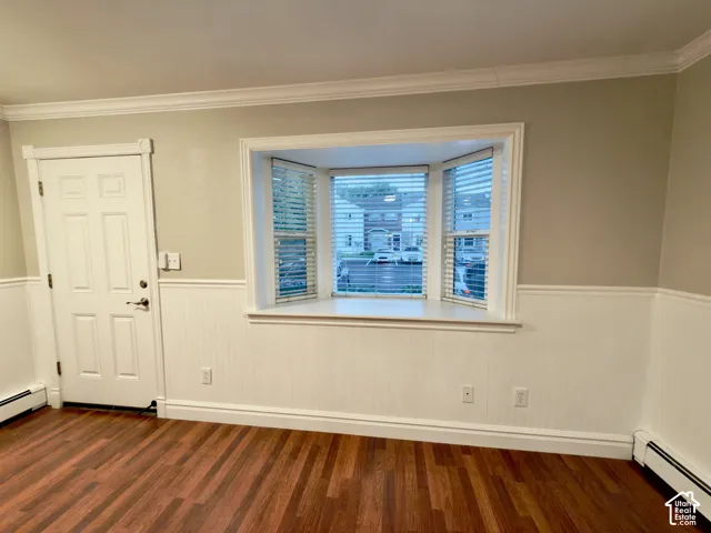Laminate flooring, bright bay window, white wainscoting, crown molding, and a paneled entry door