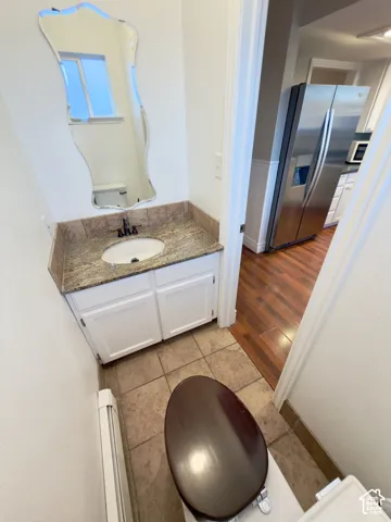 Half bathroom with vanity, a decorative mirror and granite countertop, & tile flooring