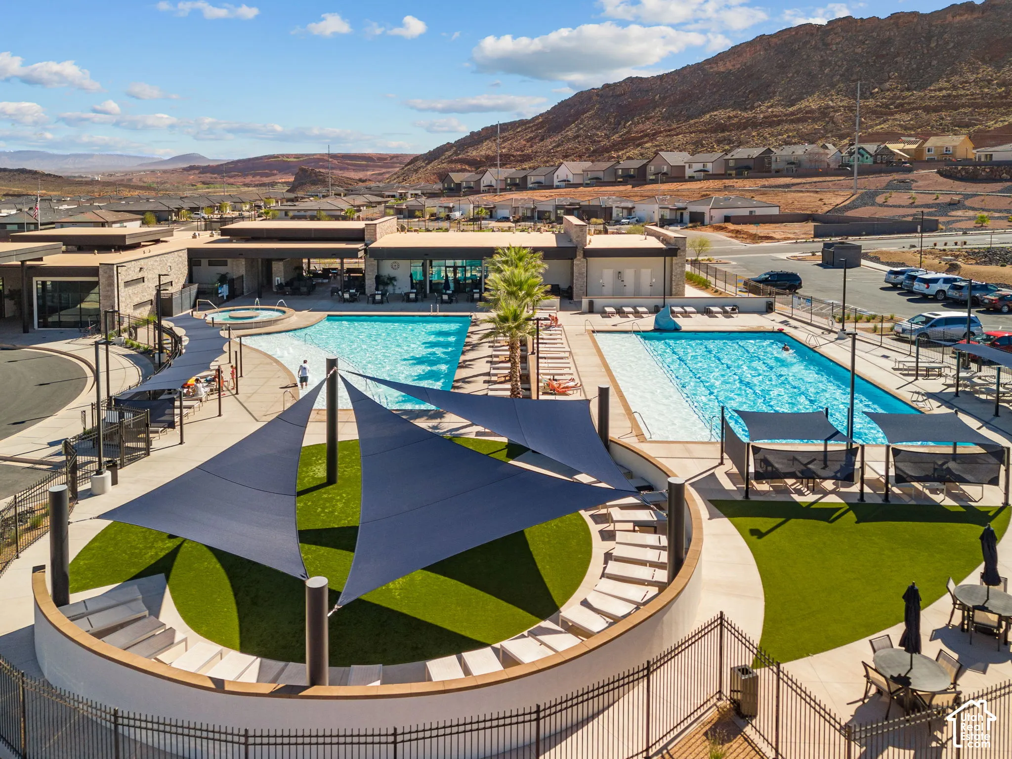 Community amenity center featuring multiple pools, a spa, and sun shade structures with artificial turf areas