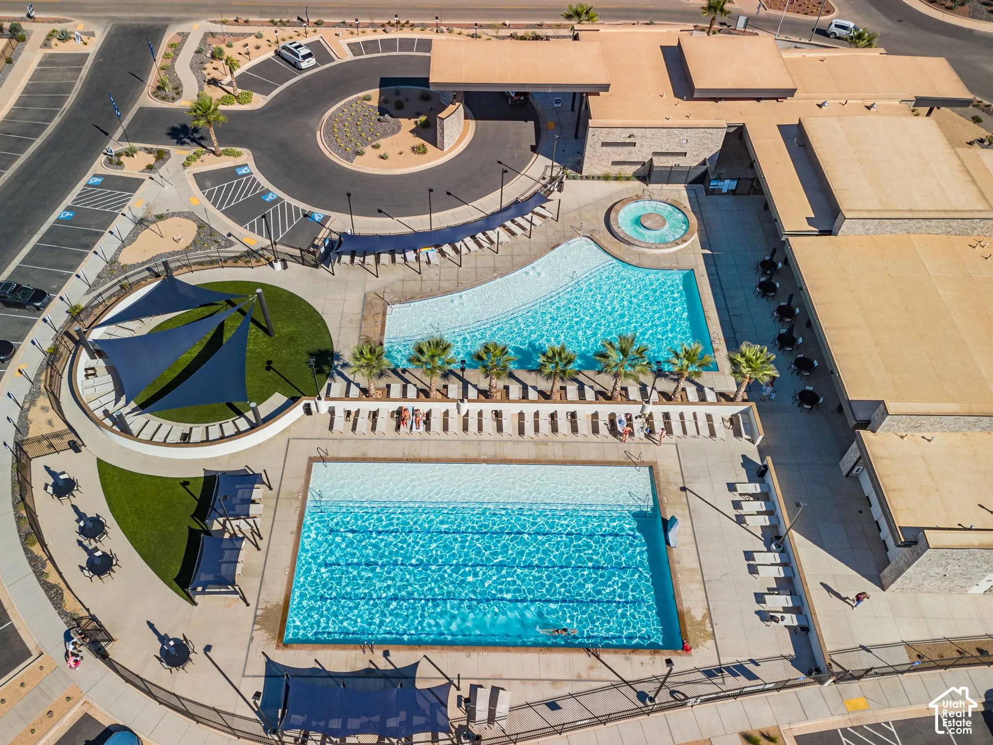 Expansive aquatic area featuring two swimming pools, a circular spa, sun shade structures, and surrounding hardscaping
