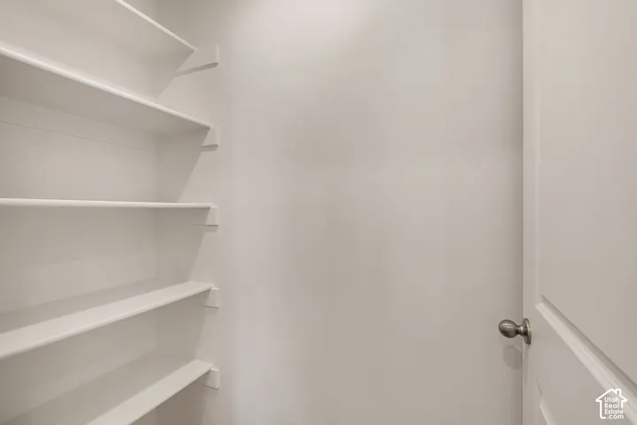 Built-in shelving with multiple levels, white painted walls, and a white paneled door with a brushed nickel doorknob