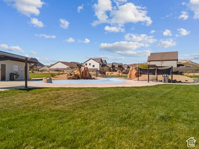 Expansive green space featuring a splash pad, shade structures, and adjacent community building