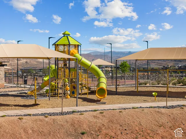 Playground featuring multiple slides, climbing structures, shaded areas, and a pea gravel surface