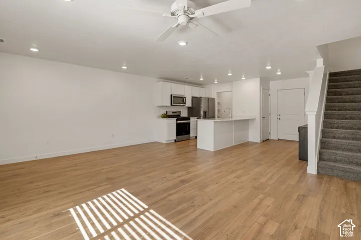Open-concept living space featuring wood-finish flooring, recessed lighting, and a white ceiling fan