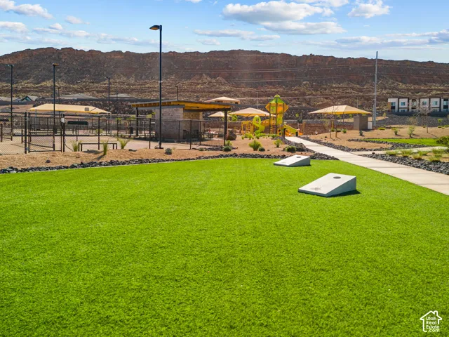 Artificial turf green space with a paved pathway and cornhole