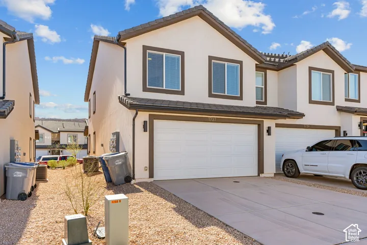 Contemporary stucco exterior with dark trim accents, attached two-car garage, and a concrete driveway