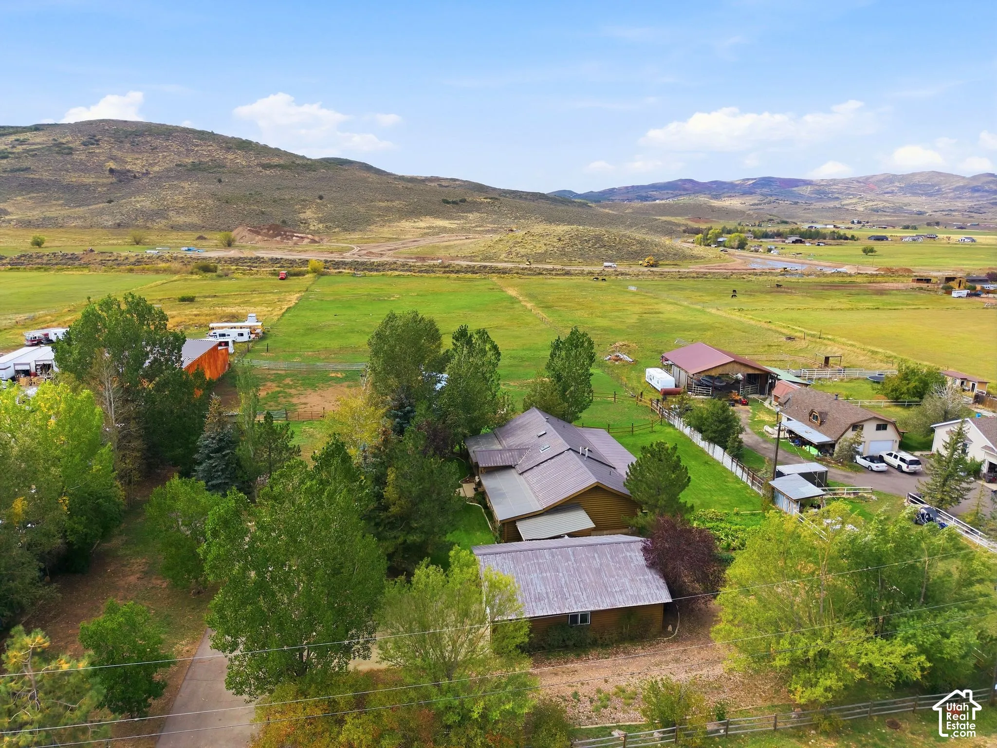Expansive property featuring multiple structures, mature trees, and vast open fields