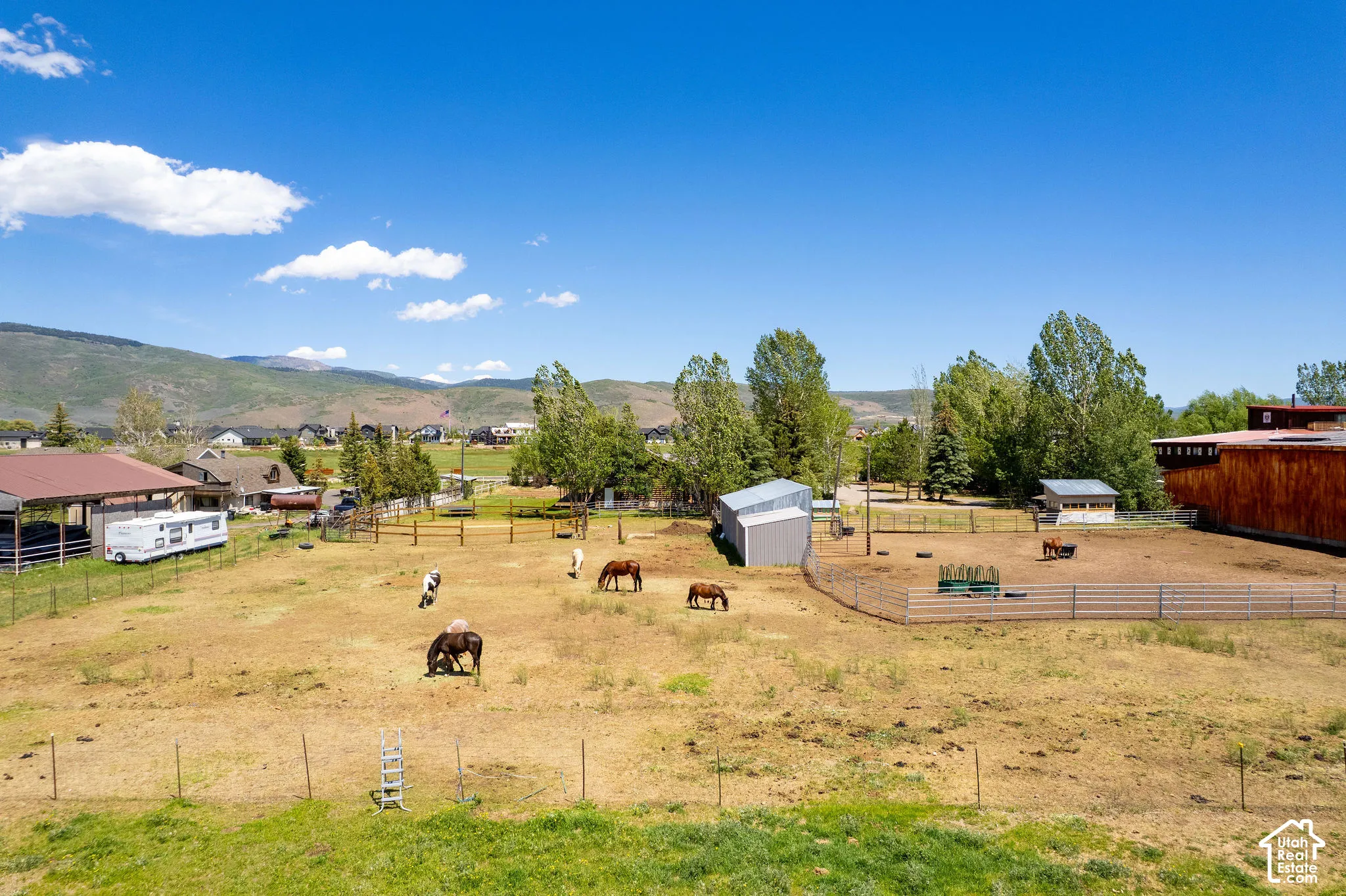 Expansive fenced pasture with multiple outbuildings and a covered structure