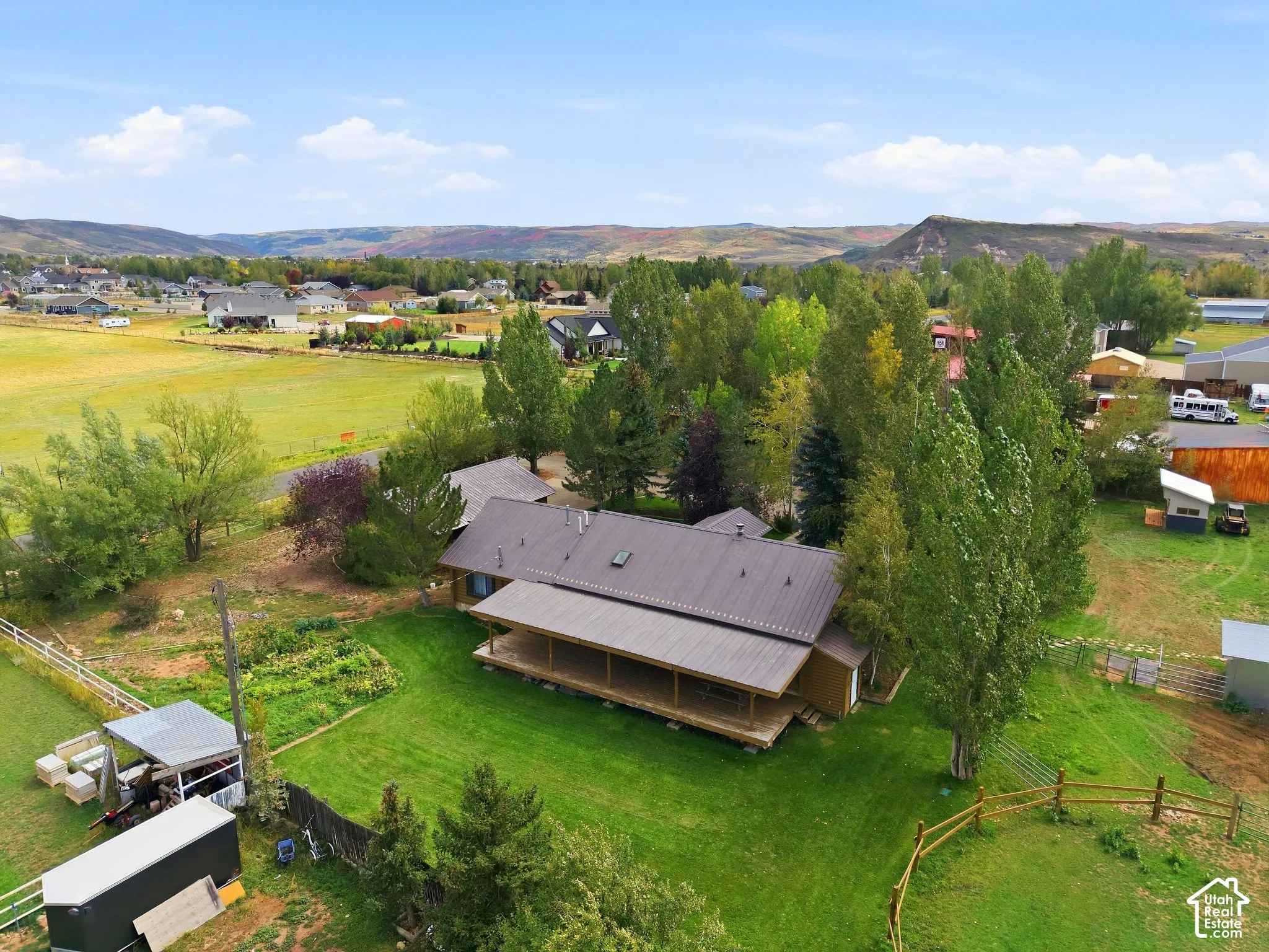 Expansive property with a metal roof residence, surrounding mature trees, and a wooden deck