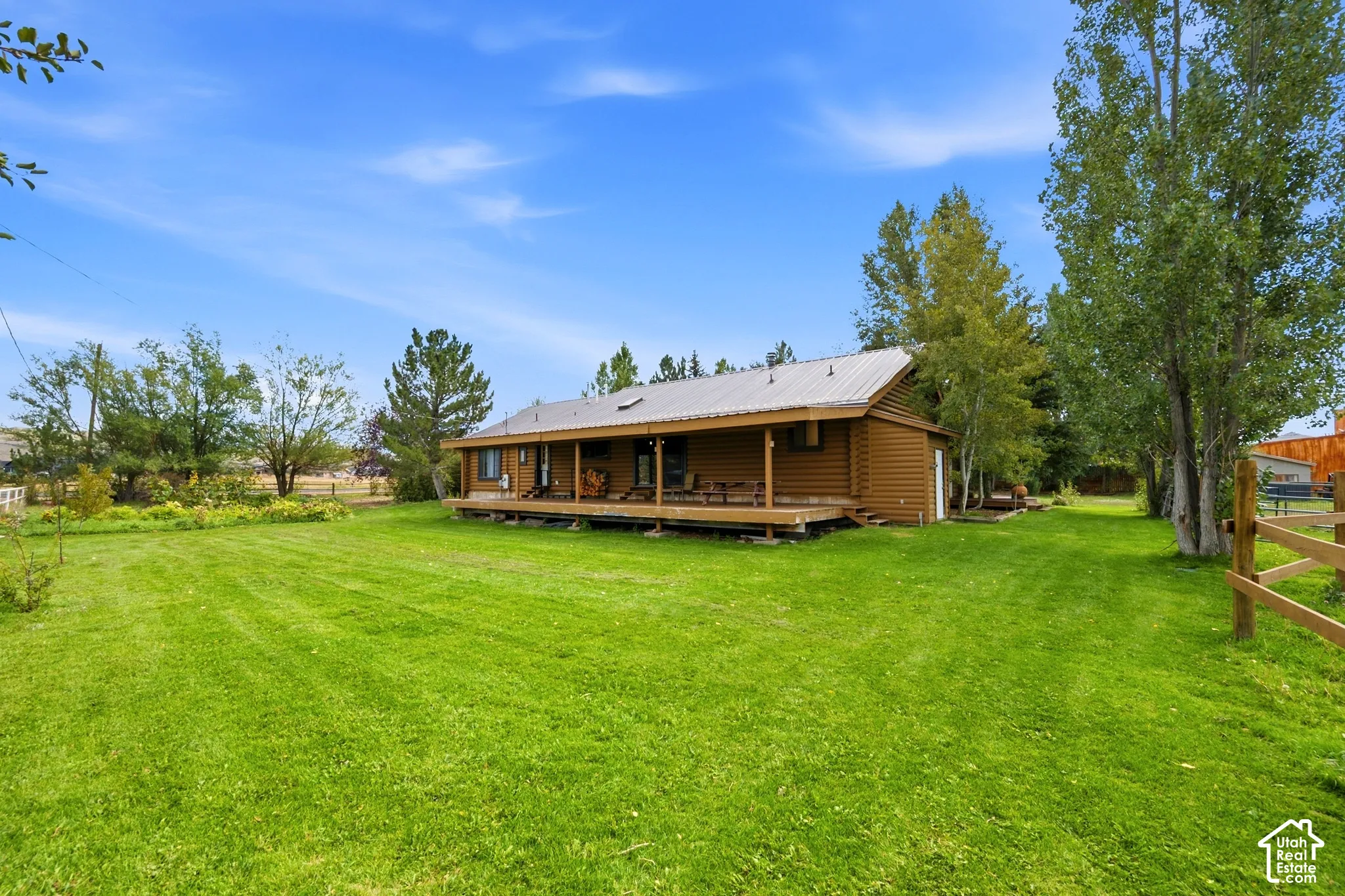 Log-sided residence with an expansive lawn, covered porch, and metal roof