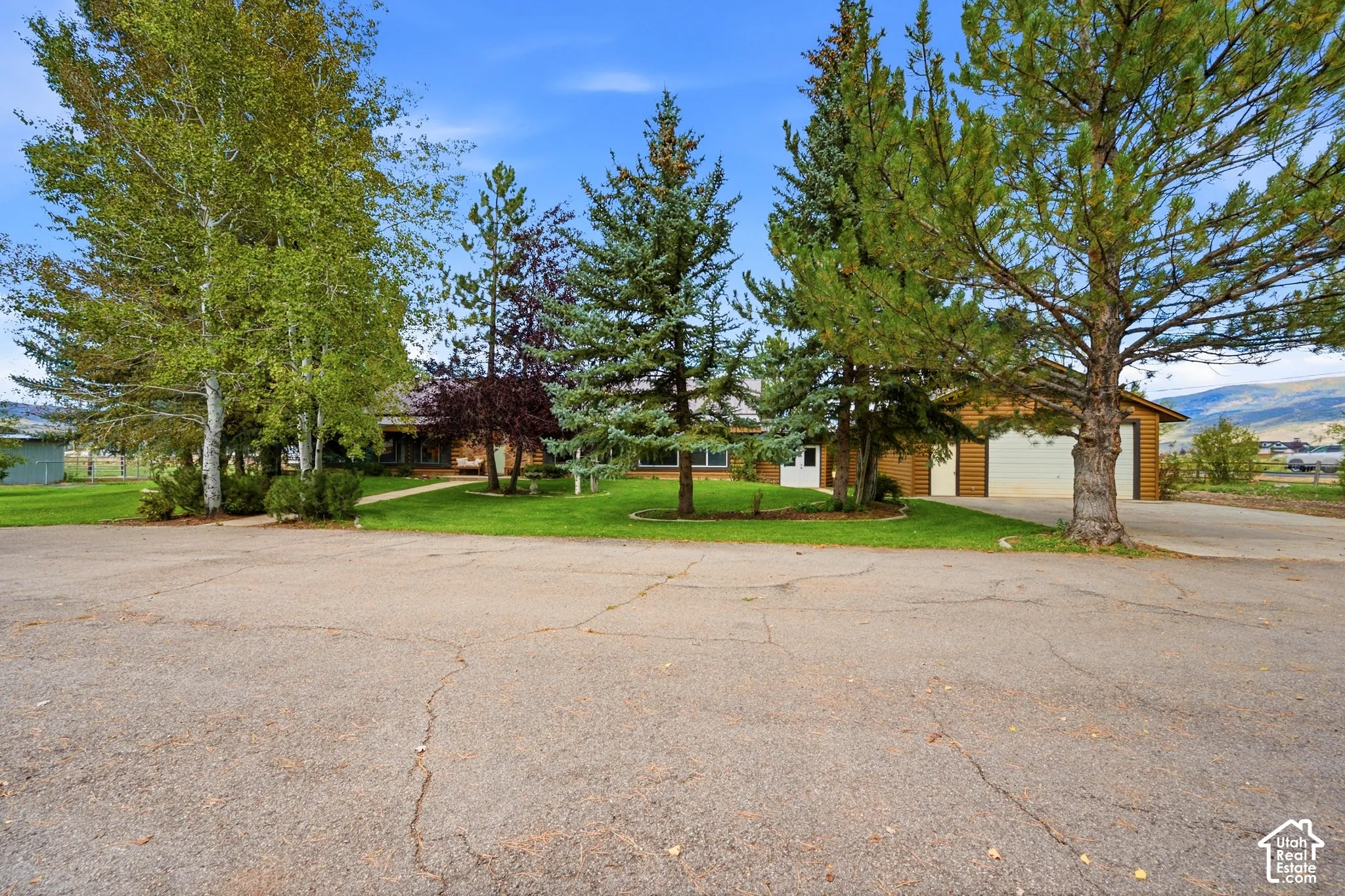 Brown siding exterior with a multi-car garage, mature trees, and a green lawn