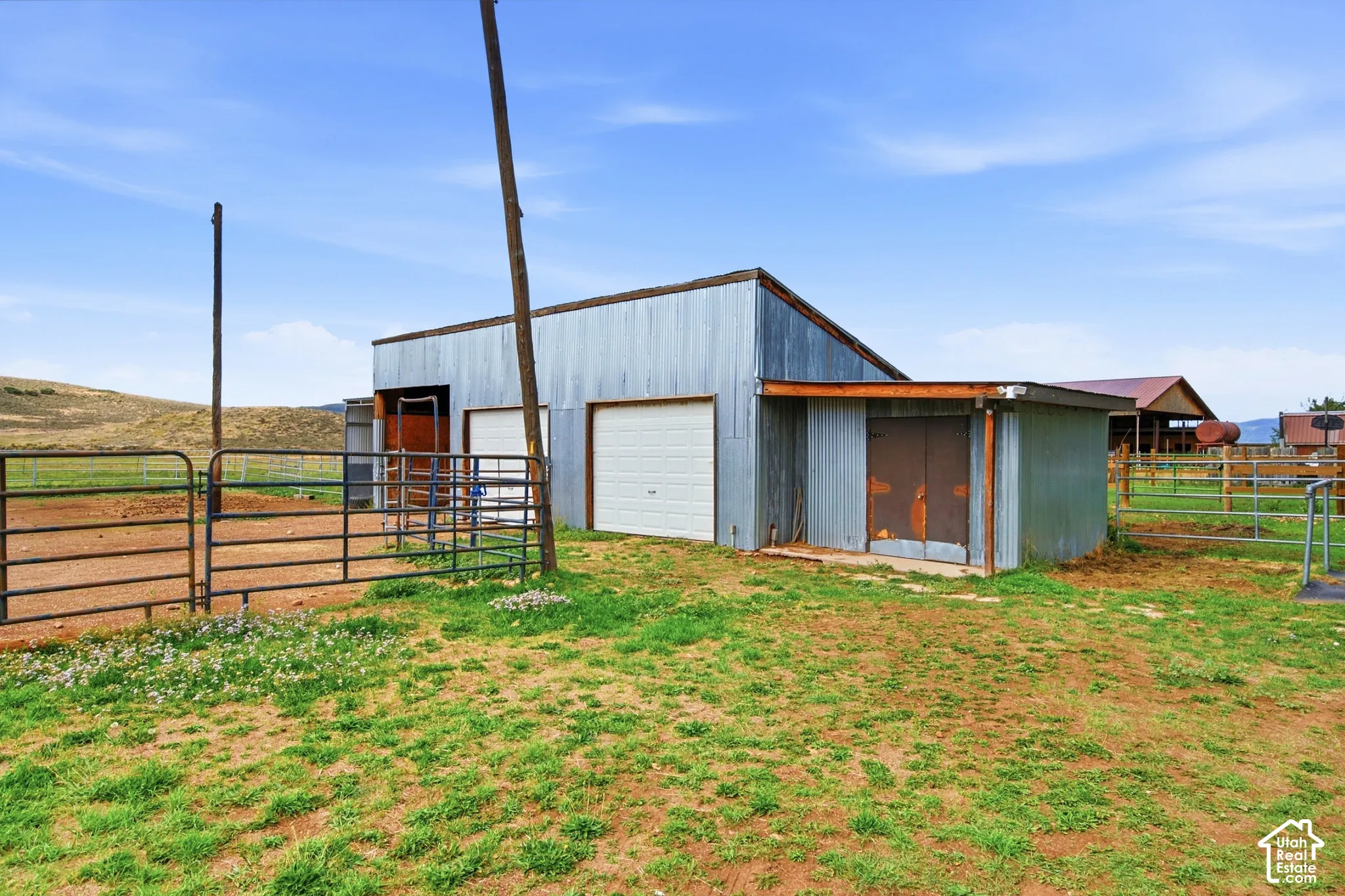 Corrugated metal building featuring two garage doors and an attached lean-to structure