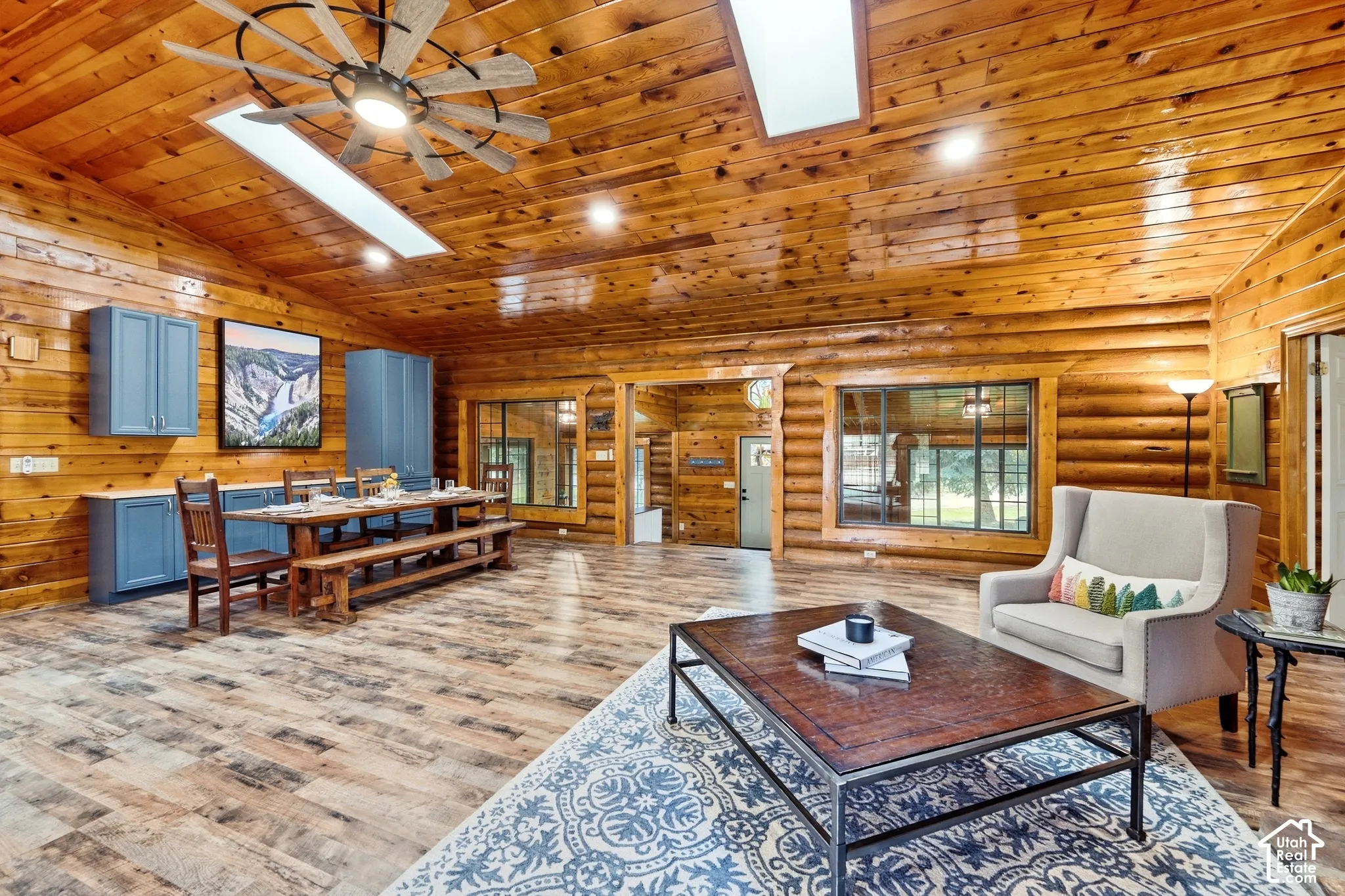 Vaulted wood-paneled ceiling, skylights, wood-finish flooring, exposed log walls, and built-in blue cabinetry