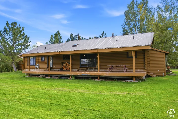 Log exterior with a covered porch, metal roof, and skylight