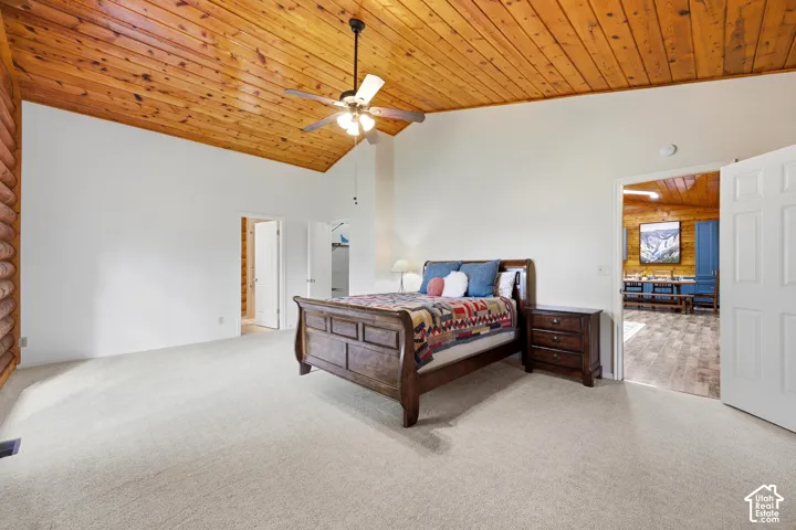 Vaulted wood-paneled ceiling with a ceiling fan, white walls, and light-toned carpeting
