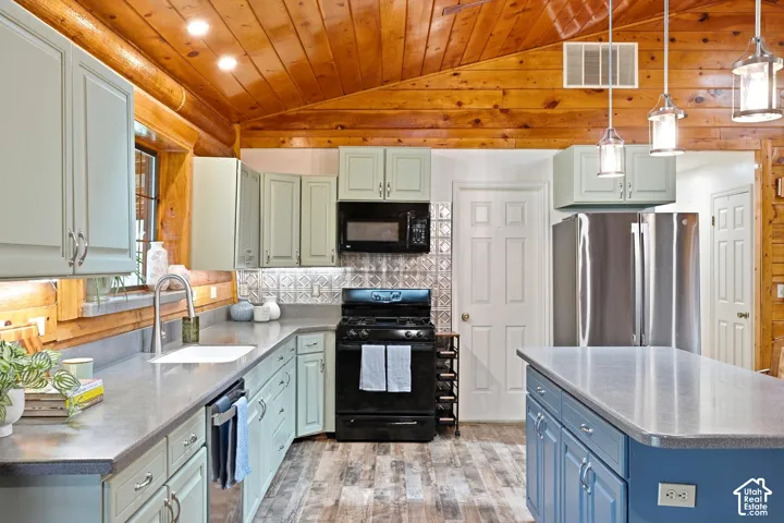 Kitchen featuring a vaulted wood-paneled ceiling, light-toned cabinetry, stainless steel refrigerator, black range, and an island with pendant lighting