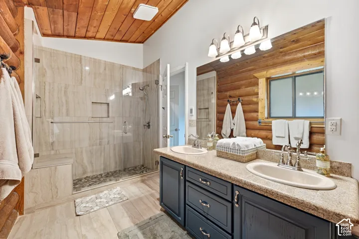 Dual vanity with oval sinks, stone-finish countertop, and dark wood-finish cabinetry