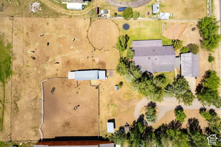 Ranch property featuring multiple fenced pastures, a large primary residence with a metal roof, an additional outbuilding with a metal roof, and established trees