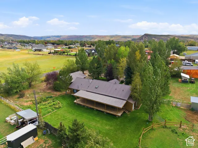 Expansive property with a metal roof residence, surrounding mature trees, and a wooden deck