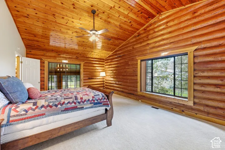 Wood-paneled vaulted ceiling, log walls, and a large window with grid pattern