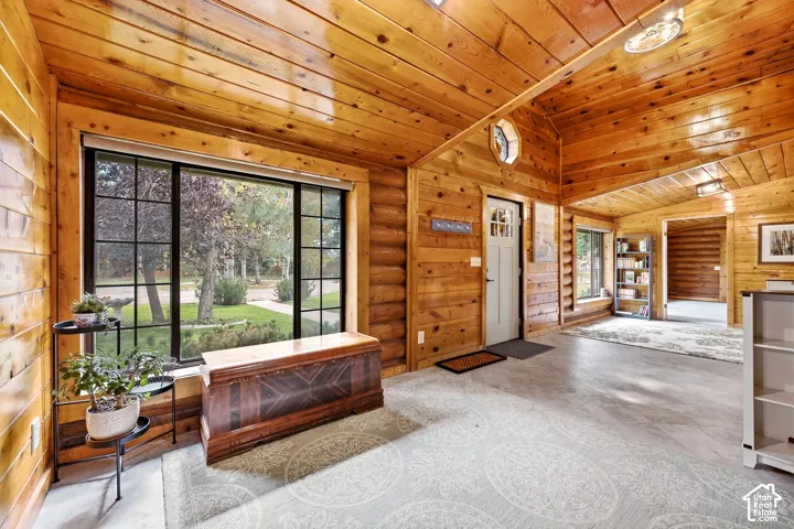 Exposed wood paneling and log walls, vaulted wood-finish ceiling, large multi-pane window, and recessed lighting