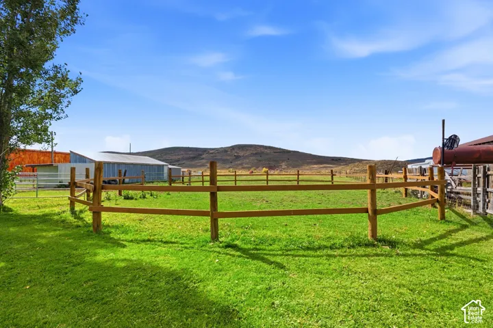Expansive green pasture with wood fencing, featuring a distant mountain backdrop