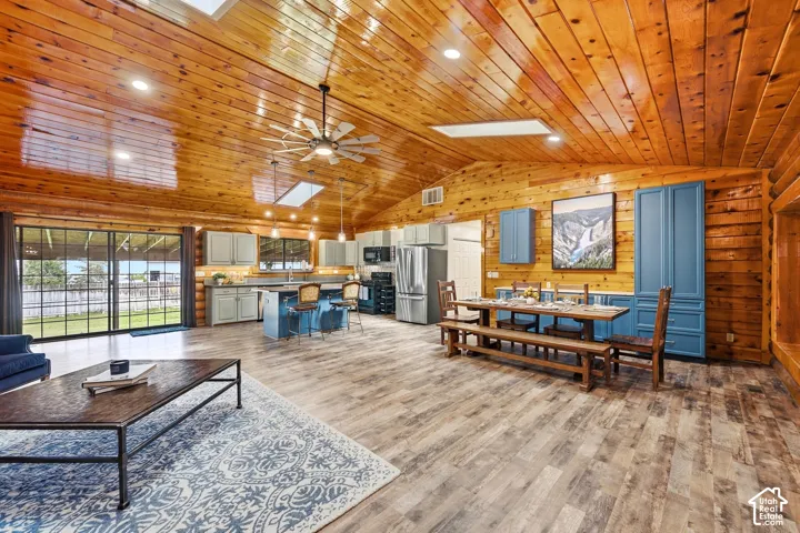 Vaulted wood-paneled ceiling with skylights and recessed lighting, wood-finish flooring, sliding glass doors, and a kitchen island with built-in cabinetry