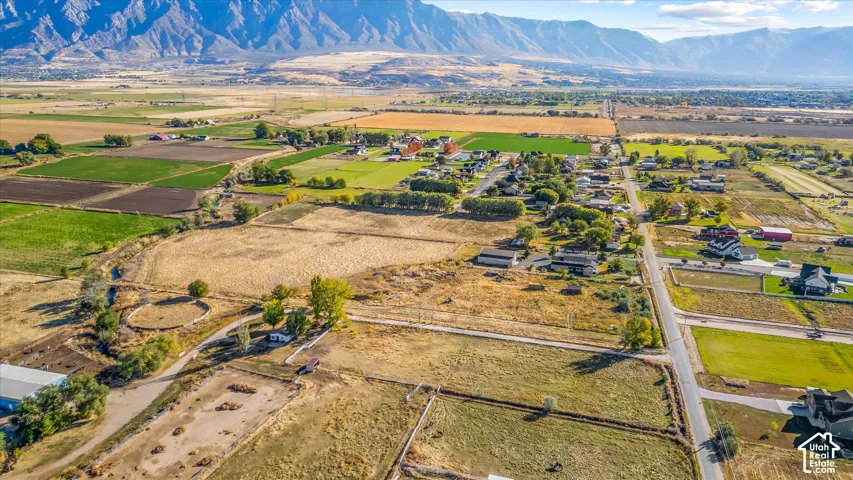 Expansive rural landscape featuring a mountainous backdrop, agricultural fields, and a network of roads