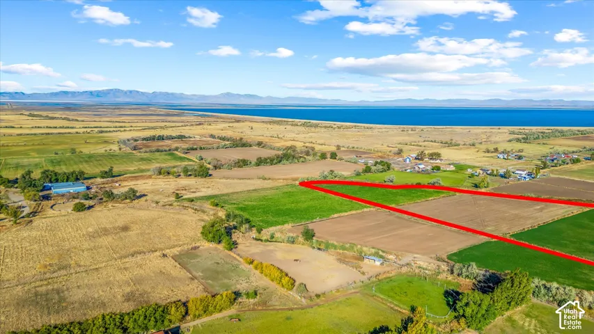 Expansive land with a prominent body of water, distant mountains, and varied agricultural fields