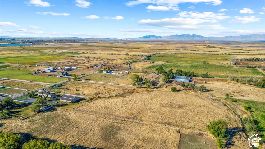 Expansive agricultural property featuring multiple structures, open fields, and distant mountain ranges