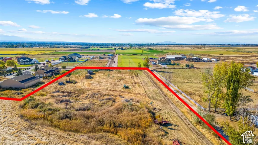 Expansive lot with a defined property boundary, surrounded by open fields and distant residential structures