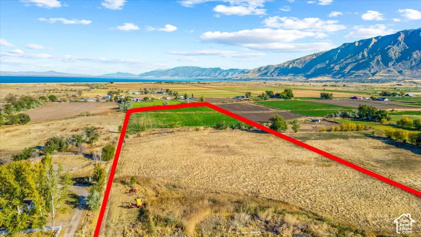 Expansive parcel with diverse terrain, featuring a clear property boundary, distant water body, and surrounding mountain ranges