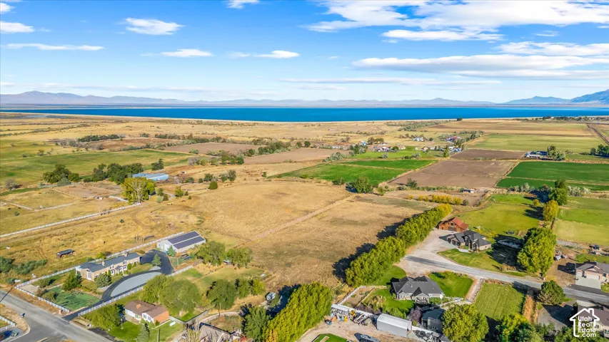 Expansive land featuring a large body of water, distant mountains, and established properties with surrounding vegetation