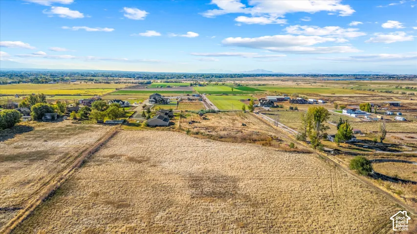 Expansive undeveloped land featuring a rural setting with distant mountains and scattered residential properties
